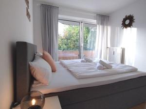 1 dormitorio con 1 cama blanca grande y ventana en Cozy home - Willkommen in Aachen - Boxspringbett - Balkon 