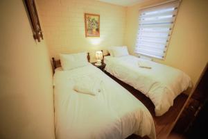 2 camas individuales en una habitación con ventana en Departamento las Torres, en Punta Arenas
