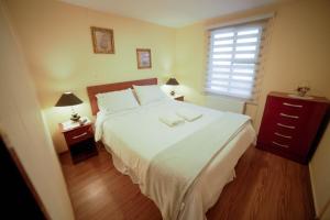 Un dormitorio con una gran cama blanca y una ventana en Departamento las Torres, en Punta Arenas