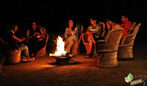 a group of people sitting around a fire at Aspen Adventures Camp by Aspen in Rishīkesh