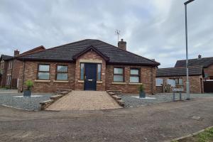 a brick house with a blue door on a street at Millhouse Cottage A Luxury 3 bed Bungalow in Antrim