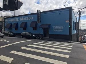 duży niebieski budynek z samochodami zaparkowanymi przed nim w obiekcie Hotel Marabá w mieście Jundiaí