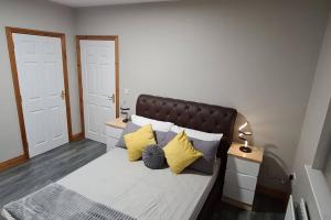 een slaapkamer met een bed met gele en grijze kussens bij Millhouse Cottage A Luxury 3 bed Bungalow in Antrim