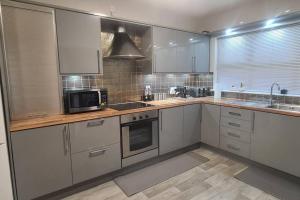 a kitchen with white cabinets and a sink and a microwave at Millhouse Cottage A Luxury 3 bed Bungalow in Antrim