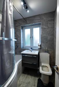 baño con lavabo y aseo y ventana en UPPAMOST LUXURY HOME LONDOn, en Dagenham