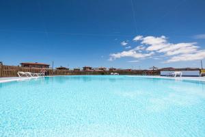 a large pool of blue water with white chairs at Villardilla Fuerteventura in La Oliva