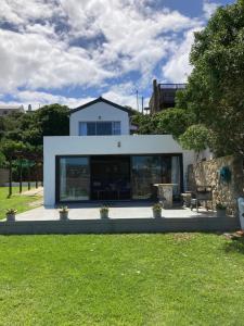 a white house with glass windows and a green yard at Waterford Holiday Home in Witsand