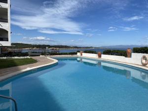 een groot zwembad met uitzicht op het water bij Maravilloso apartamento PRIMERA LINEA DE MAR in L'Escala