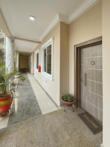 a hallway of a building with a door and plants at Cozy Apartments East Legon in Accra