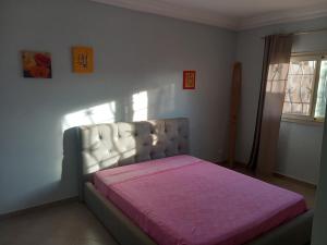 Un dormitorio con una cama con una manta rosa. en Casa Kassi en Ndéyane