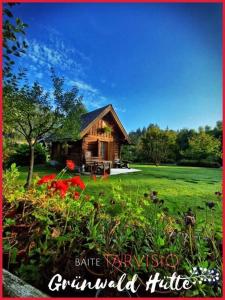 uma cabana de madeira no meio de um campo com flores em Grünwald Hütte em Tarvisio