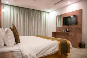 a hotel room with a bed and a flat screen tv at Areen Hotel Al Basateen in Jeddah