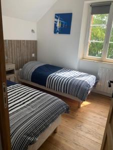 two beds in a room with a window at La maisonnette de la gare in Montmartin-sur-Mer