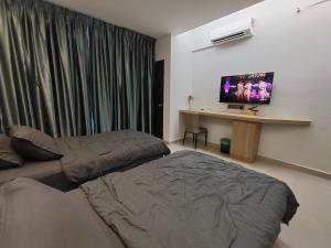 een slaapkamer met 2 bedden, een bureau en een televisie bij Hanan Studio Apartment with Pool, Wifi & Netflix in Gua Musang