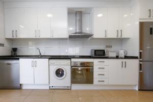 a kitchen with white cabinets and a washing machine at Nina Villa Planetcostadorada in Tarragona