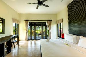 a bedroom with a bed and a desk and windows at Phukhaolak Resort in Khao Lak