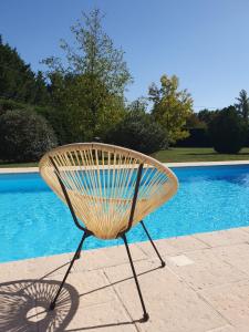 un banco de madera sentado junto a una piscina en Suite spacieuse avec entrée privative en Lédat