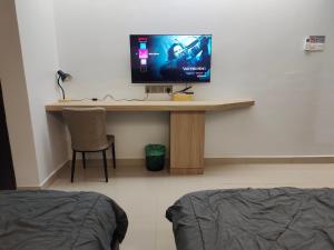 Habitación con escritorio y TV en la pared. en Hanan Studio Apartment with Pool, Wifi & Netflix, en Gua Musang