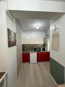 uma cozinha com armários vermelhos e electrodomésticos brancos em Antonette 2 Apartment Mamaia Nord em Mamaia Nord – Năvodari