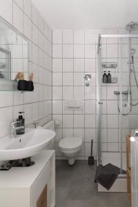 e bagno con servizi igienici, lavandino e doccia. di Ilmpartment - Vollausstattung - Boxspringbett - Wi-Fi - Netflix a Ilmenau