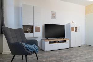 a living room with a television and a chair at Ilmpartment - Vollausstattung - Boxspringbett - Wi-Fi - Netflix in Ilmenau