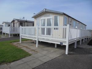 a small house with a white railing on a lot at Kingfisher Bordeaux 8 Berth Central Heated FREE WIFI in Ingoldmells