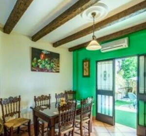 une salle à manger avec des murs verts, une table et des chaises dans l'établissement 2 bedrooms house with private pool and terrace at El Bosque, à El Bosque