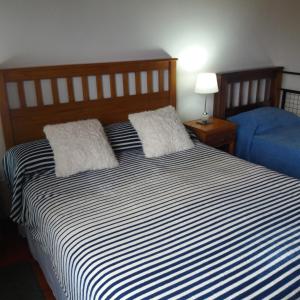 ein Schlafzimmer mit einem schwarz-weißen gestreiften Bett mit einem blauen Stuhl in der Unterkunft Amancay in Villa Elisa