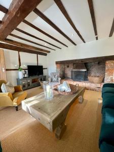 a living room with a table and a fireplace at Mimosa Cottage in Farnham
