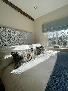 a bedroom with a bed with pillows and a window at Mimosa Cottage in Farnham