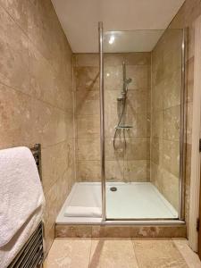 una doccia con una porta in vetro in un bagno di Mimosa Cottage a Farnham