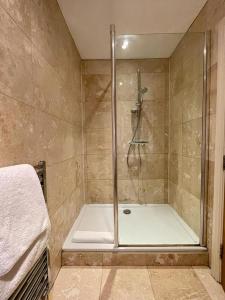 a shower with a glass door in a bathroom at Mimosa Cottage in Farnham