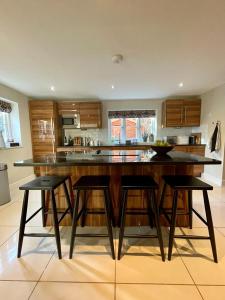a kitchen with a large island with four bar stools at Mimosa Cottage in Farnham