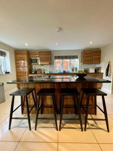 una cucina con una grande isola con quattro sgabelli da bar di Mimosa Cottage a Farnham