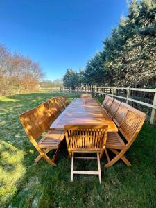 a wooden picnic table with chairs in the grass at Mimosa Cottage in Farnham