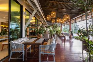 un restaurante con mesa, sillas y ventanas en Phukhaolak Resort, en Khao Lak