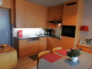 eine Küche mit Holzschränken und einem Tisch mit einem roten Tischtuch in der Unterkunft De Strandwandeling 0203 Appartement met frontaal zeezicht in Ostende