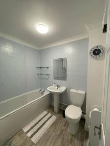 a bathroom with a toilet and a sink and a tub at Eaton Ford Green Ground Floor Apartment in Saint Neots