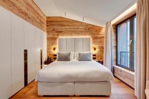 - une chambre avec un lit blanc et des murs en bois dans l'établissement Grand Hôtel des Alpes, à Chamonix-Mont-Blanc