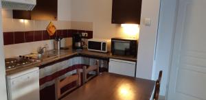 uma pequena cozinha com uma mesa e um micro-ondas em Charmant logement avec piscine em Bergerac