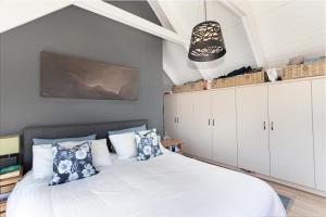 een slaapkamer met een wit bed met blauwe kussens bij Big Bay Hilltop Villa in Kaapstad