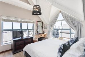een slaapkamer met een bed en een groot raam bij Big Bay Hilltop Villa in Kaapstad