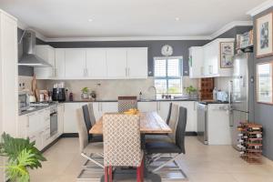 een keuken met witte kasten en een houten tafel en stoelen bij Big Bay Hilltop Villa in Kaapstad