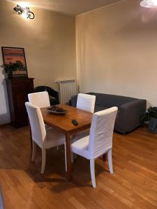 mesa de comedor con 4 sillas blancas y sofá en Cozy Nest, en Milán