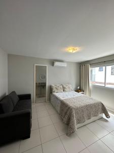 um quarto com uma cama e um sofá em Apartamento 3 Quartos em Frente à Praia do Forte em Cabo Frio