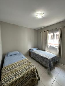 sypialnia z 2 łóżkami i oknem w obiekcie Apartamento 3 Quartos em Frente à Praia do Forte w mieście Cabo Frio