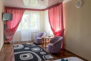 Zimmer mit 2 Stühlen, einem Tisch und einem Fenster in der Unterkunft Дуглас in Petropawlowsk