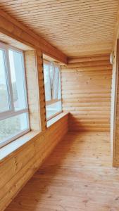 een lege kamer met twee ramen in een houten huis bij Будинок з Терасою Біля Фонтанів in Oeman