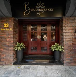 une porte d'entrée d'un bâtiment avec deux plantes en pot dans l'établissement Bonjour D'An Nam Hotel, à Hanoï