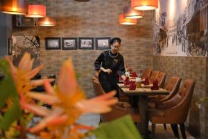 um homem parado em frente a uma mesa num restaurante em Bonjour D'An Nam Hotel em Hanói